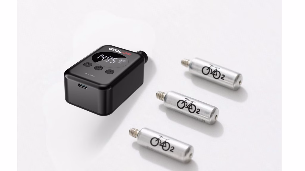Mini electric bike pump compared with CO₂ cartridges on a white background